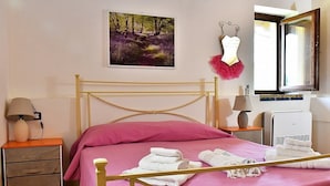 Une chambre à coucher comprenant un lit, une table de chevet, une lampe, un miroir et un tableau accroché au mur.