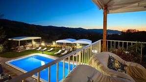 Un espace aménagé au bord de la piscine offrant une vue dégagée sur le paysage environnant, notamment les collines et le panorama urbain au loin.