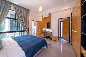 A modern bedroom with a large bed, a TV, and a sliding door leading to a balcony. - bangtao 3BR Modern Villa Wallaya Harmony (Phuket)