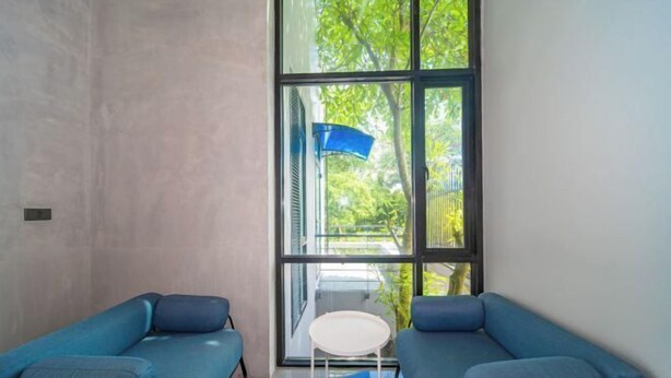 A room with two blue sofas, a small white table, and a large window with a view of greenery.