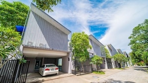 A modern residential building with a car parked in the driveway.
