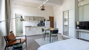 A modern hotel room with a bed, a desk, and a kitchenette. - The Printhouse Boutique Studio 4 (Haifa)