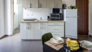 A modern kitchen with white cabinets, a microwave, a coffee maker, and a refrigerator. - The Printhouse Boutique Studio 4 (Haifa)