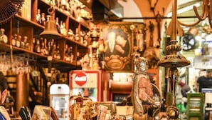 A cluttered antique shop with various items on display, including a bell, a statue, and a vintage fan. - The Printhouse Boutique Studio 4 (Haifa)