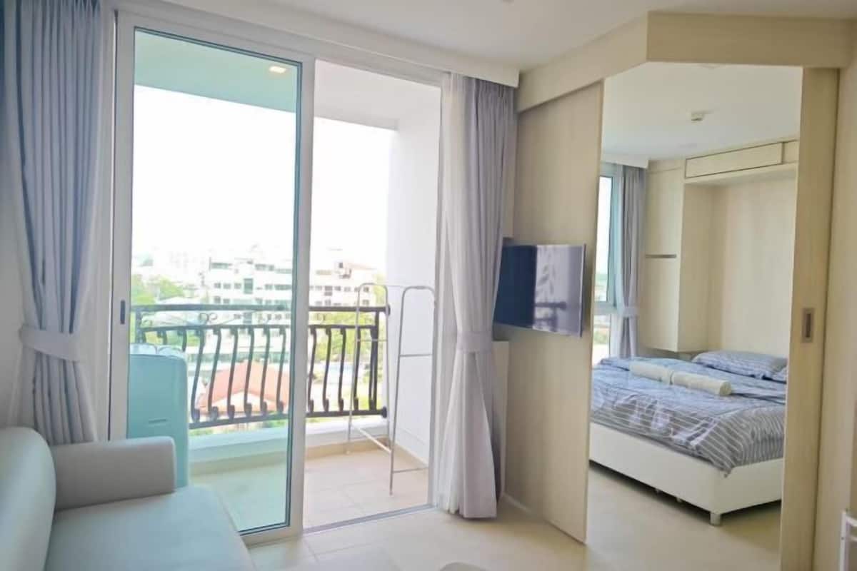 Habitación de hotel con balcón, una cama, televisión y vistas de la ciudad.