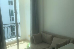 A balcony with a metal railing, a beige sofa, and a window with curtains. - City Garden pool condo (Pattaya)