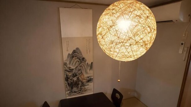Un espace repas comprenant une table, des chaises, un luminaire suspendu et une œuvre d’art fixée au mur.