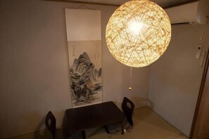 A dining area with a table, chairs, a hanging light fixture, and a wall-mounted artwork. - KIRAKU･NIJO (Kyoto)