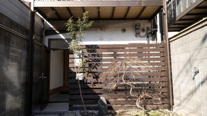 Une ruelle étroite, bordée d’une clôture en bois, avec un petit arbre et un chemin pavé de pierres.