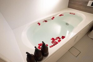 A bathtub with rose petals and three bottles of bath products. - KIRAKU･NIJO (Kyoto)