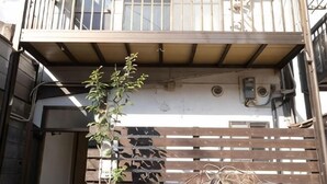 Un bâtiment doté d’un balcon, d’une clôture en bois et d’une plante.
