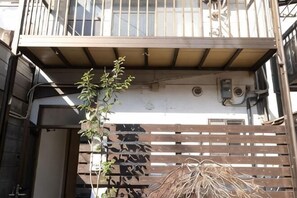 Un edificio con un balcón, una valla de madera y una planta.