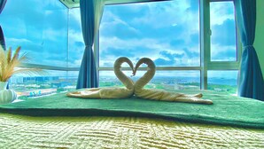 Una stanza con un'ampia finestra, una coperta verde e un'accattivante composizione di asciugamani a forma di cuore.