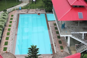 Una piscina rectangular con un borde de ladrillo y pequeños parches de césped.
