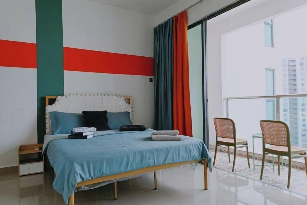 Ein modernes Schlafzimmer mit Bett, Nachttisch und Balkon mit Sitzgelegenheiten.