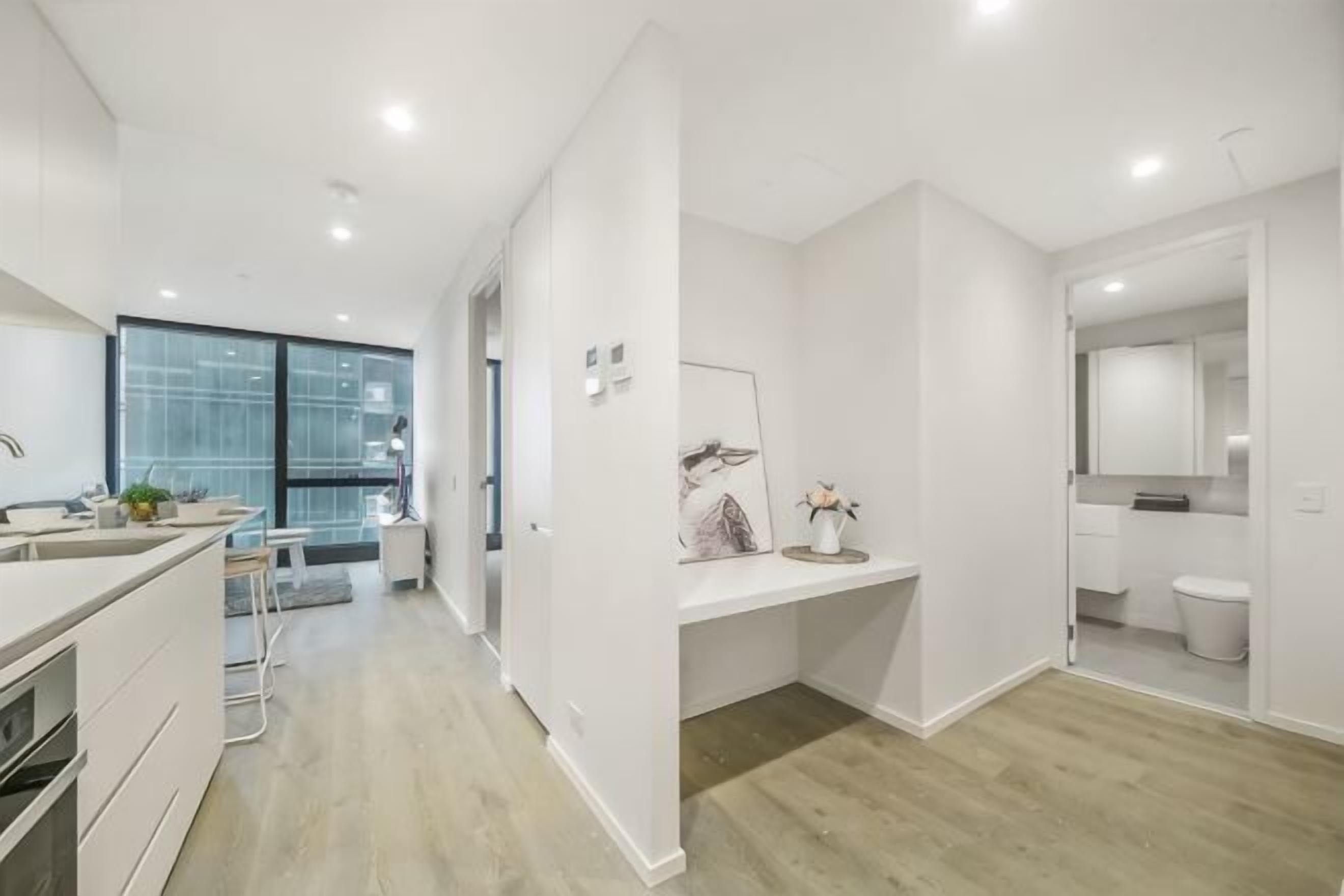 A modern kitchen with a dining area, a large window, and a bathroom with a mirror and toilet.