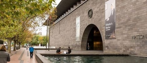 A building with a brick facade, a water feature in front, and a staircase leading to an upper level.