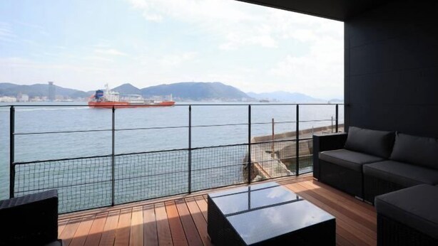 A balcony with a view of a river, a boat, and distant mountains. - Dannoura Strait Villa (Shimonoseki)