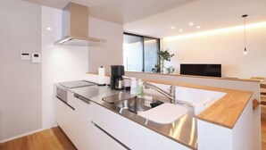 A modern kitchen with a stainless steel sink, a built-in oven, and a coffee maker. - Dannoura Strait Villa (Shimonoseki)