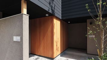 A modern building with a wooden structure, a concrete wall, and a small tree.