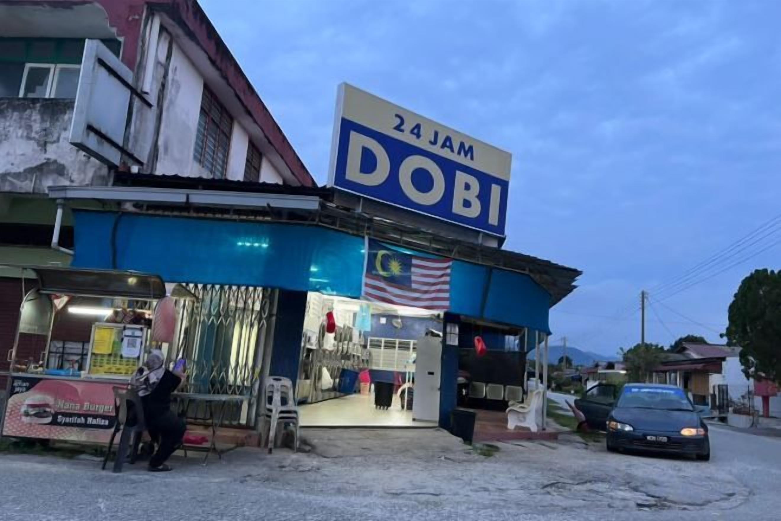 A 24-hour convenience store with a prominent sign, a small entrance, and a parked car outside.