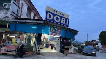 A 24-hour convenience store with a prominent sign, a small entrance, and a parked car outside.