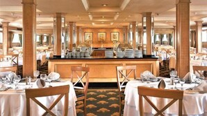 Un restaurant spacieux avec de hauts plafonds, de grandes fenêtres et un bar central.