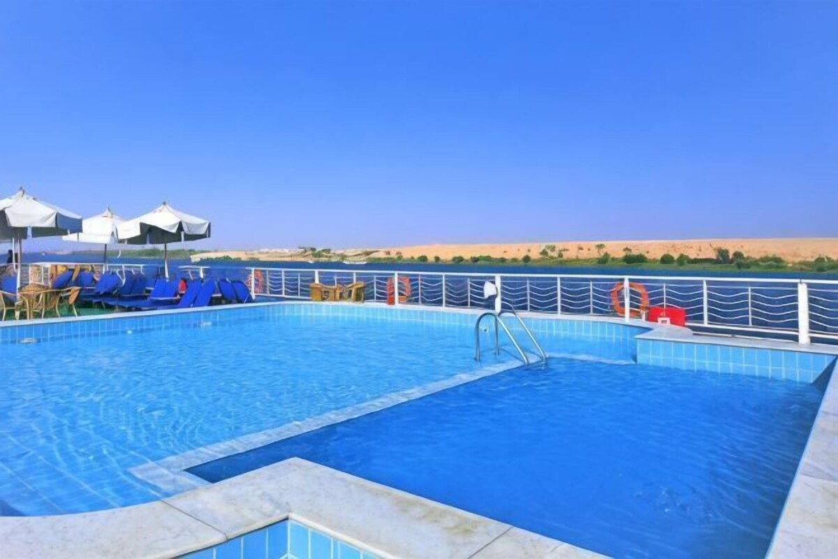 A swimming pool with blue tiles, a lifeguard stand, and lounge chairs.