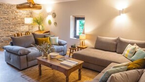 Een gezellige woonkamer met een stenen muur, een houten balk, een bank, een salontafel en een lamp.