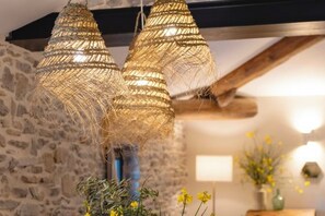 Un intérieur rustique avec des murs en pierre, des poutres apparentes et des luminaires en osier.