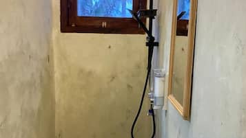 Ein Badezimmer mit Fenster, Dusche und Spiegel.