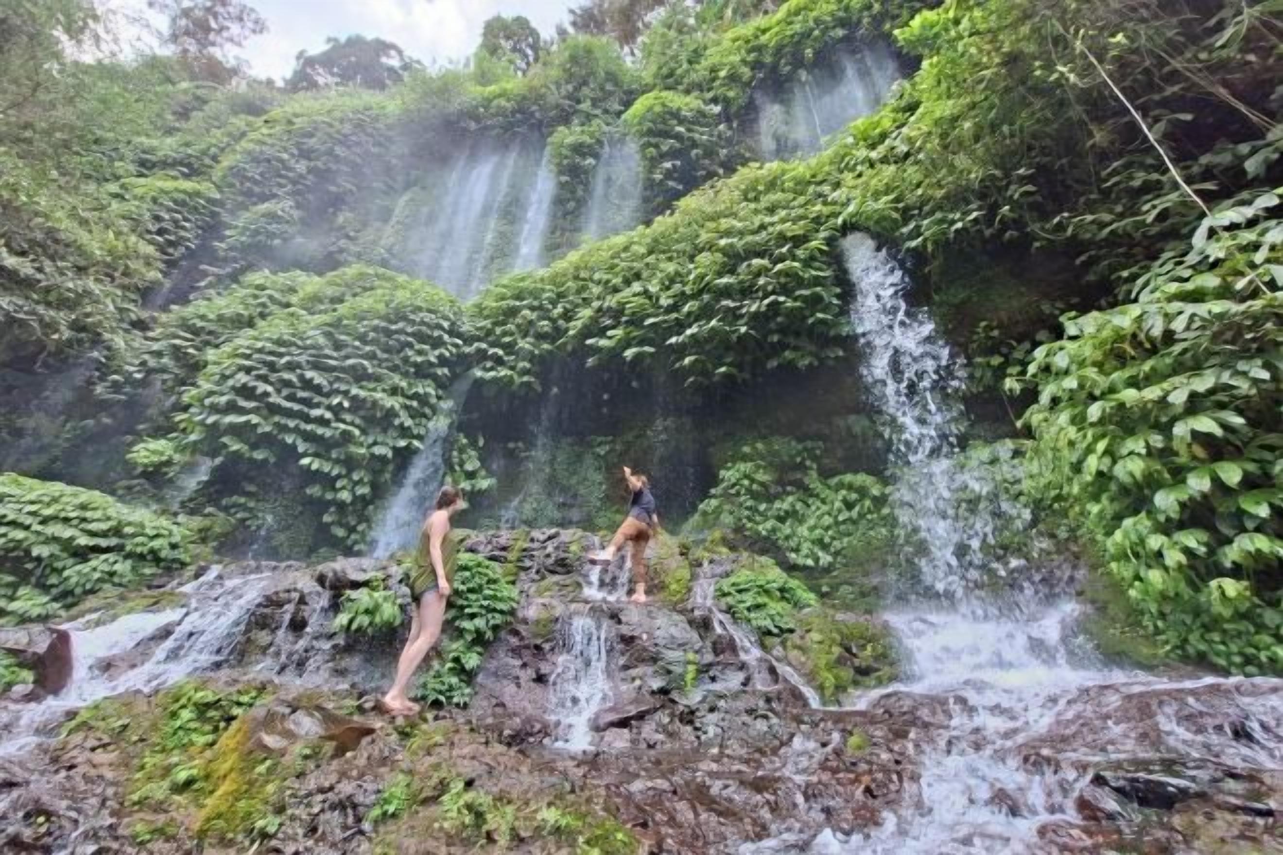 A natural waterfall with lush greenery and rocky terrain.