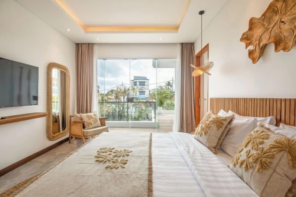 Un dormitorio moderno con una cama grande, televisión, espejo y balcón con vistas.