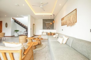 A modern living room with a grey sofa, wooden coffee table, and a staircase.