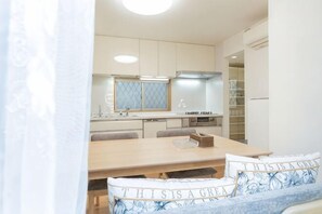 A modern kitchen with white cabinets, a wooden dining table, and a built-in oven. - lami home (Tokyo)
