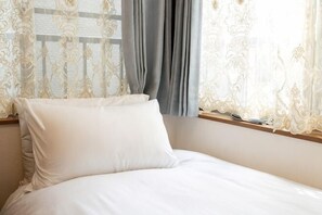 A bed with white bedding, a window with curtains, and a wooden headboard. - lami home (Tokyo)