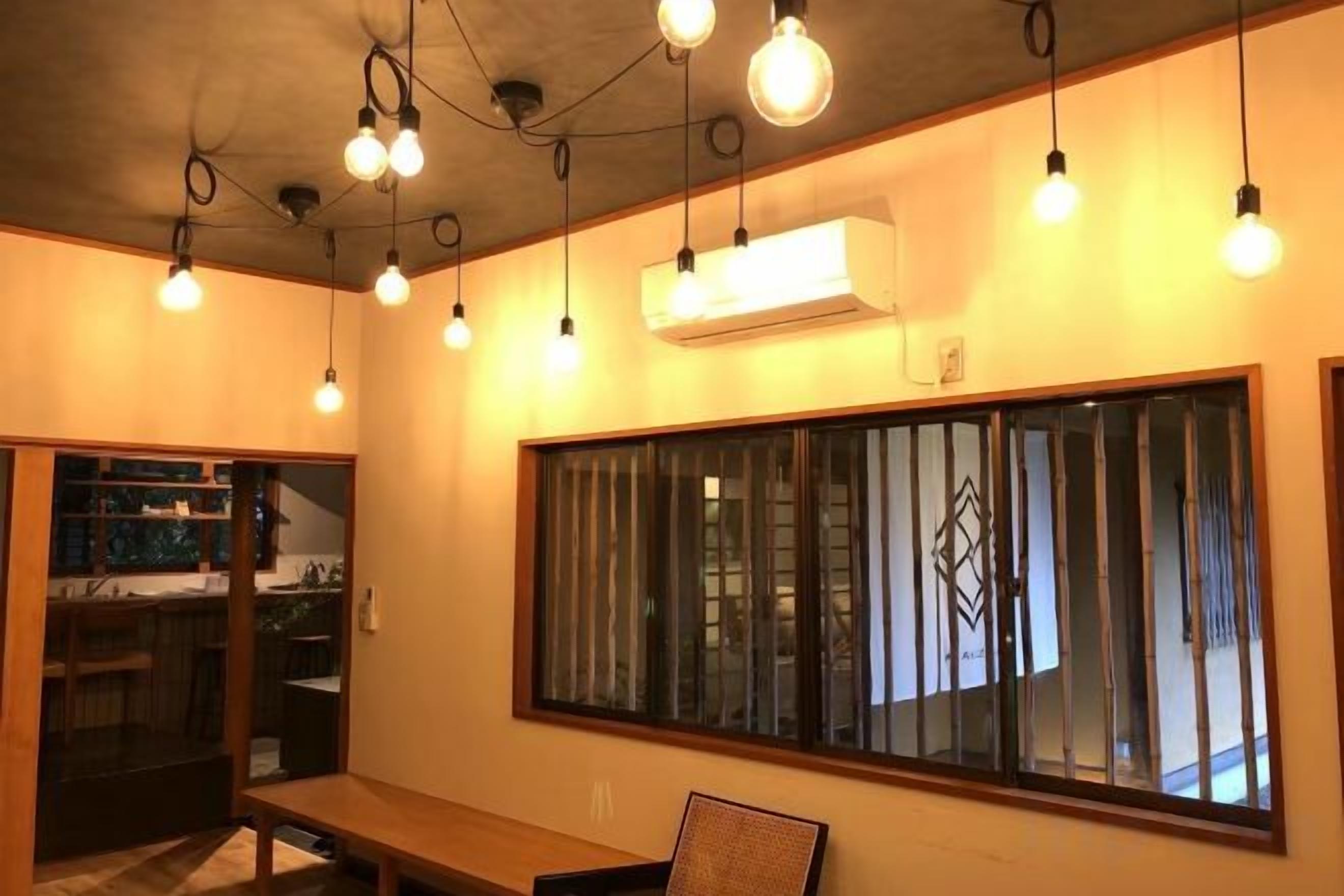 A room with a large window, a bench, and hanging light fixtures.