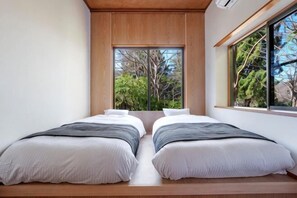 A room with two beds, a large window with a view of trees, and a wooden ceiling. - KEYAKIZAKA (Ito)