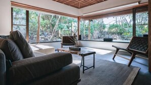 A room with a wooden ceiling, large windows, a sofa, a coffee table, and a chair. - KEYAKIZAKA (Ito)