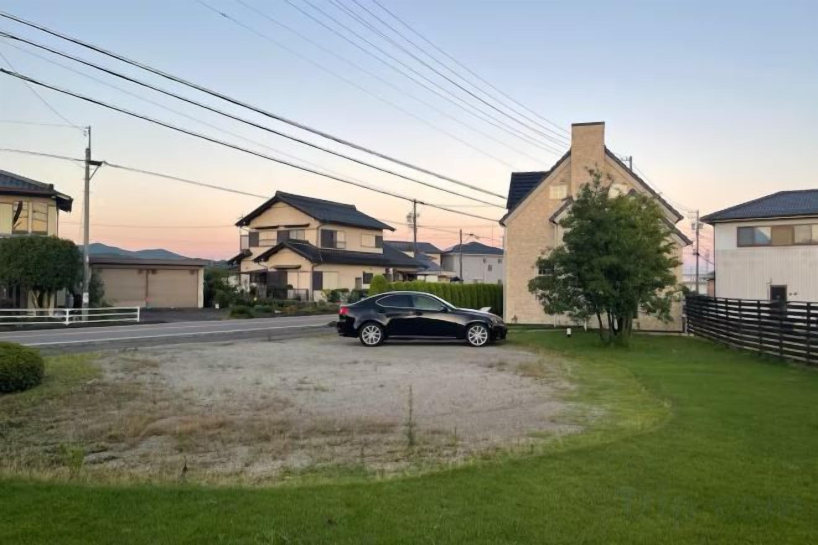 A residential area with houses, a car, and a grassy driveway.