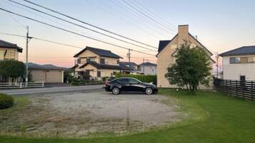 A residential area with houses, a car, and a grassy driveway.
