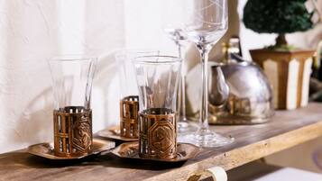 A wooden shelf with glassware and metal candle holders.