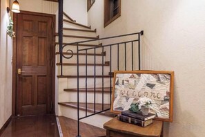 A wooden door, a staircase with a metal railing, and a welcome sign on a small table. - Antiques　Gifu Seki (Seki)