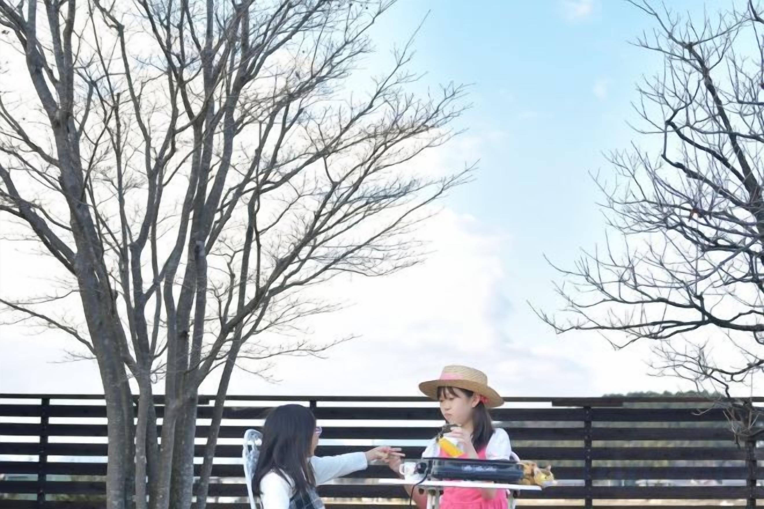 A person standing in front of a tree with a fence in the background.