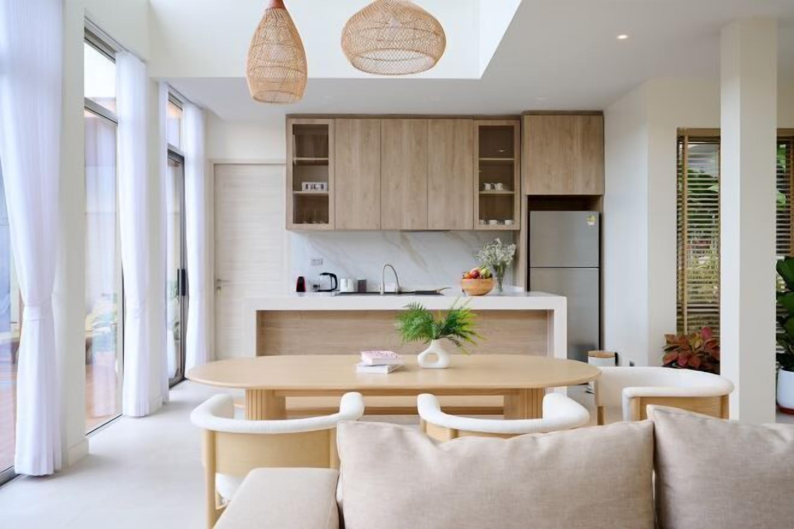A modern kitchen with wooden cabinets, a marble countertop, and a dining area with a round table and white chairs.
