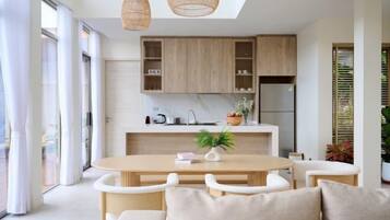 A modern kitchen with wooden cabinets, a marble countertop, and a dining area with a round table and white chairs.