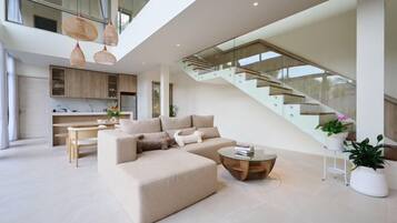 A modern living room with a sofa, coffee table, and staircase.