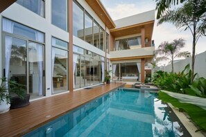 Uma casa moderna com piscina, janelas amplas e área de estar ao ar livre.