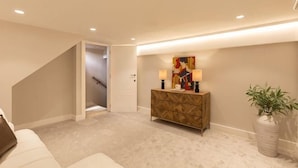 A hallway with a staircase, a console table with lamps, and a potted plant. - 311 Superior Maisonette (London)