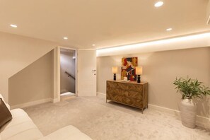 Een hal met een trap, een console tafel met lampen, en een kamerplant.